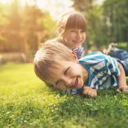 a young boy and a young girl siblings playing in the grass and smiling